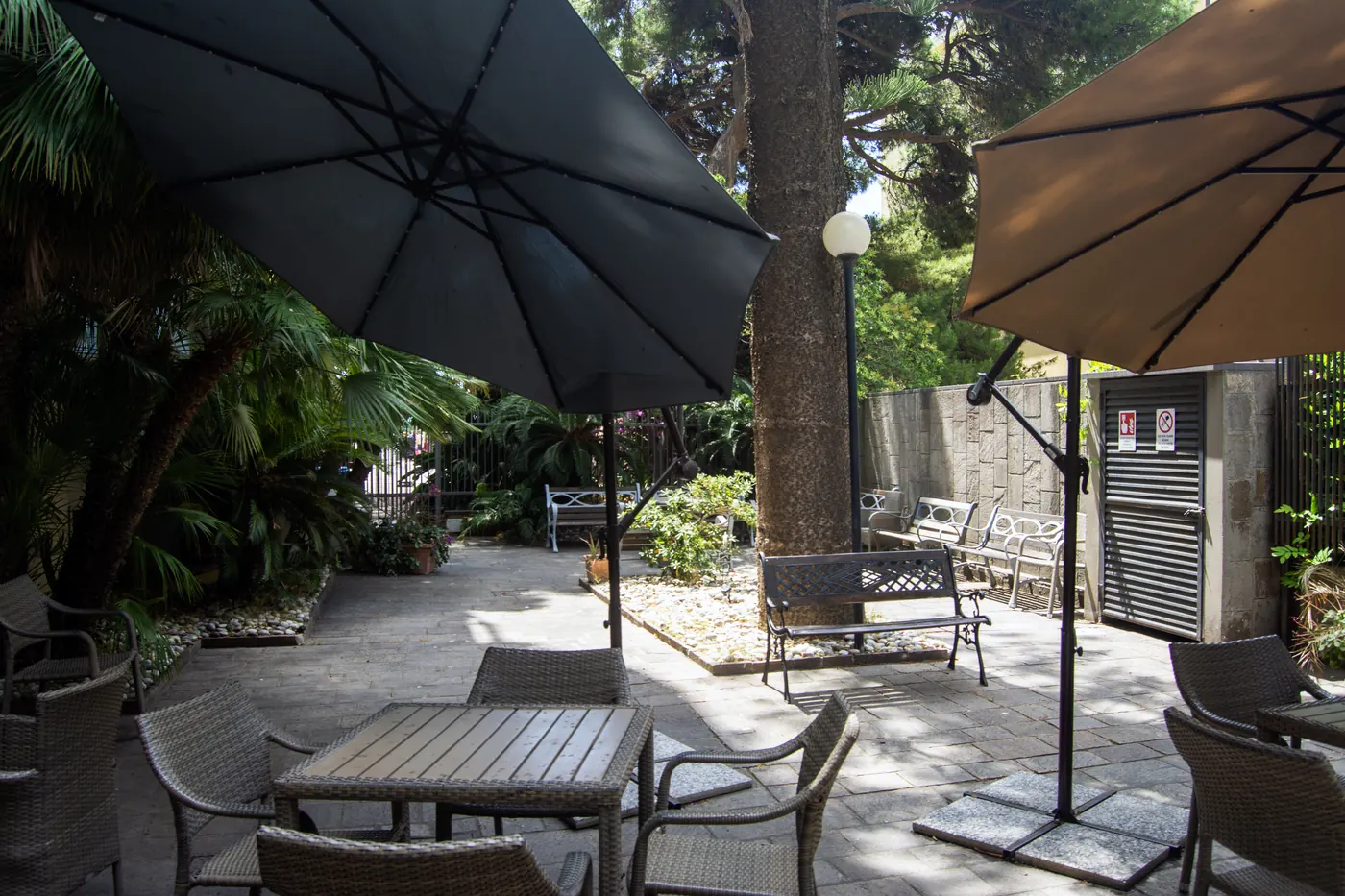 Giardino ombreggiato con tavoli e ombrelloni della RSA Le Palme, ideale per i soggiorni estivi